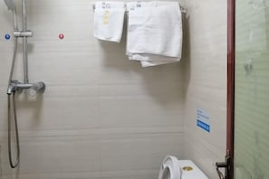 Ein Duschbereich mit Duschbrause, einem Handtuchhalter mit zwei Handtüchern, einer Toilette und einem Schild an der Wand.