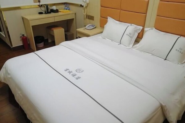 Ein Hotelzimmer mit Bett, Schreibtisch, Telefon und Feuerlöscher.