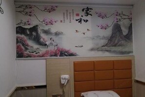Ein Zimmer mit einer traditionellen chinesischen Wandmalerei, einem Bett mit orangefarbener Kopfteil und einem an der Wand befestigten Telefon.