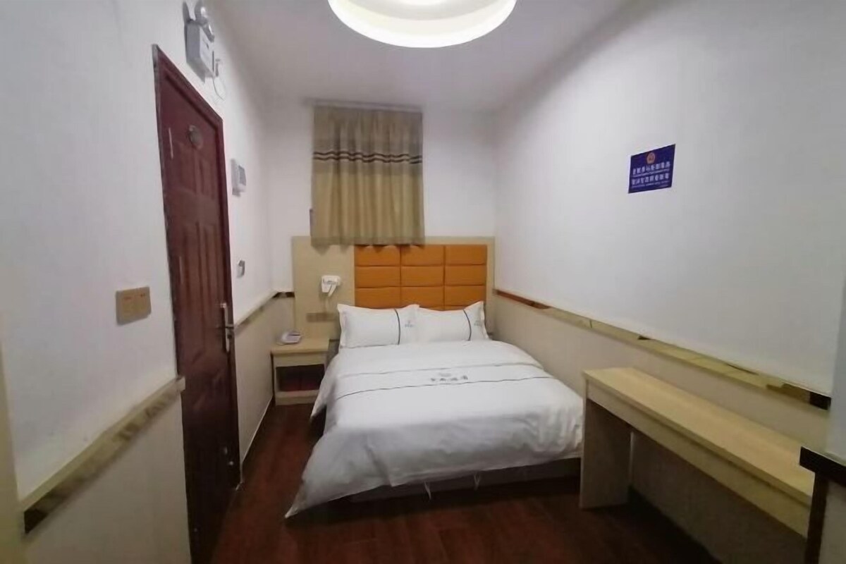 Ein Hotelzimmer mit Bett, Nachttisch, Vorhängen und einem Fenster.
