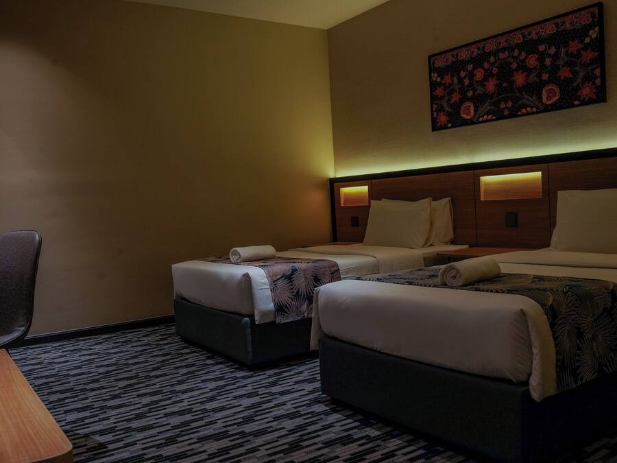 A hotel room with two beds, a desk, and a chair.