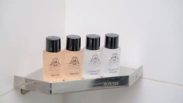 Un estante en el baño con cuatro productos de Nusa Iraman: gel de baño, champú acondicionador y champú acondicionador.