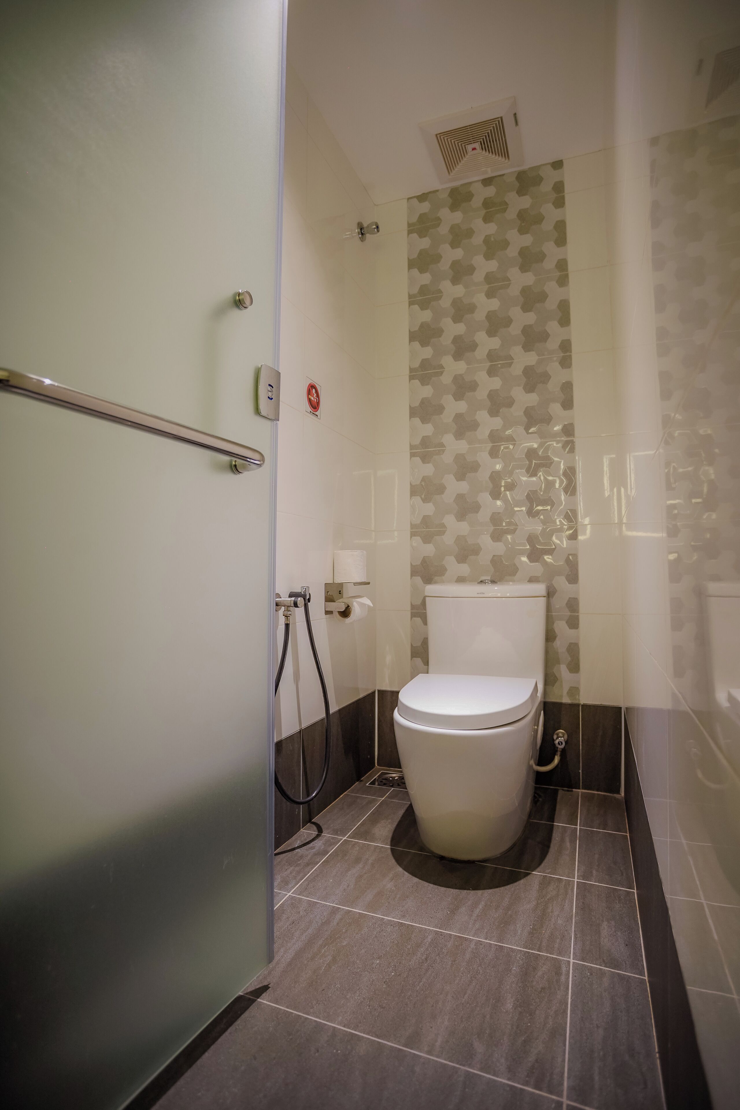 Un baño pequeño con inodoro, barra de apoyo y zona de ducha.