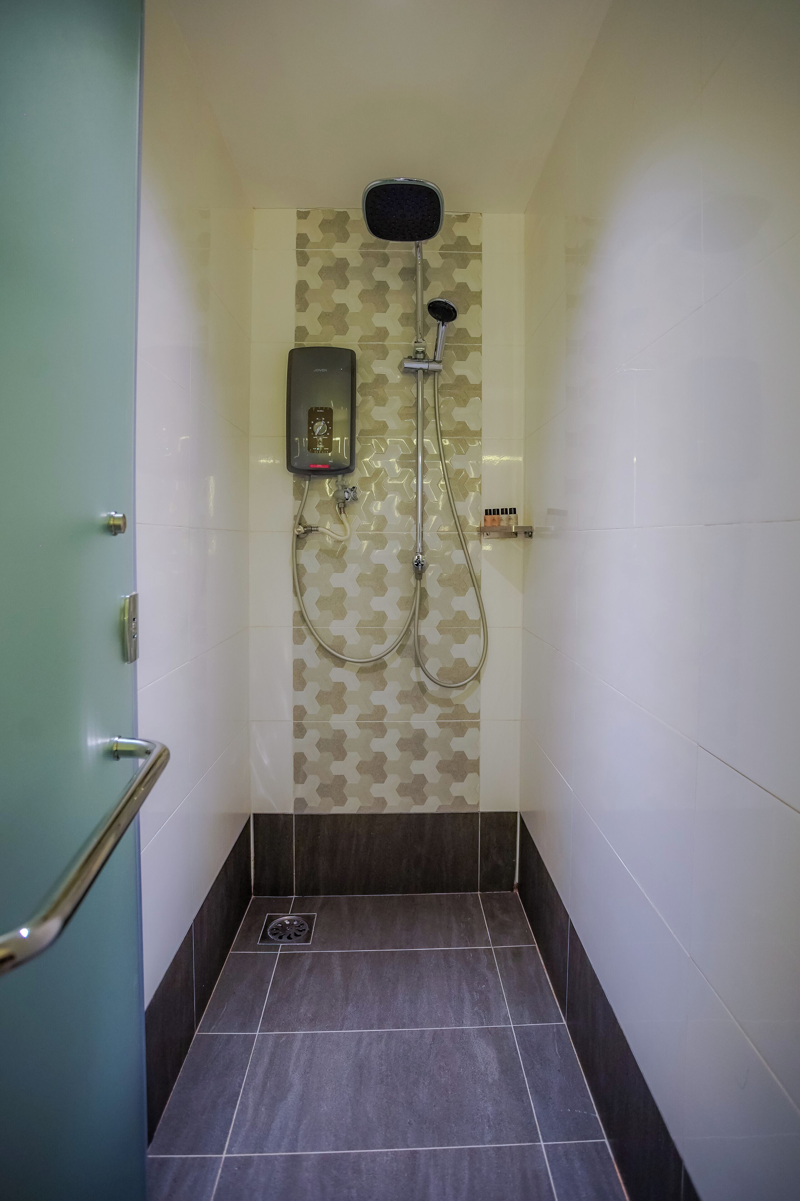 A shower with a handheld showerhead and a wall-mounted control panel.