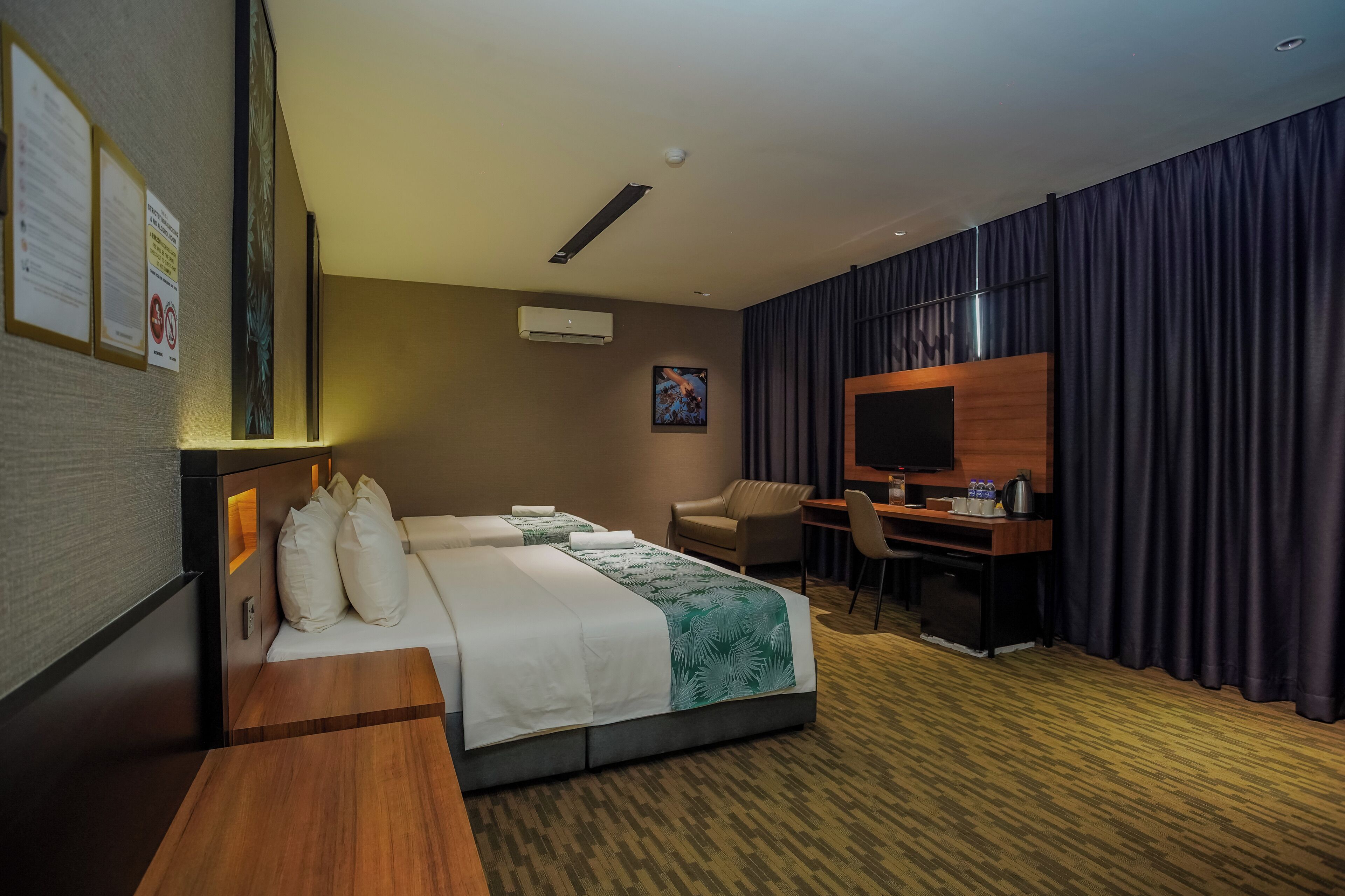 A hotel room with a bed, desk, chair, and a flat-screen TV.