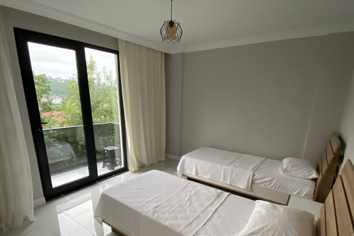 Quarto com duas camas, uma grande porta de correr de vidro e um lustre.
