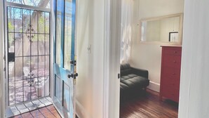 Una habitació amb terra de fusta, un sofà verd fosc, un aparador vermell i un ventilador de sostre.