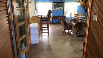 A room with a wooden door, a desk with a chair, wicker furniture, and a world map on the wall.