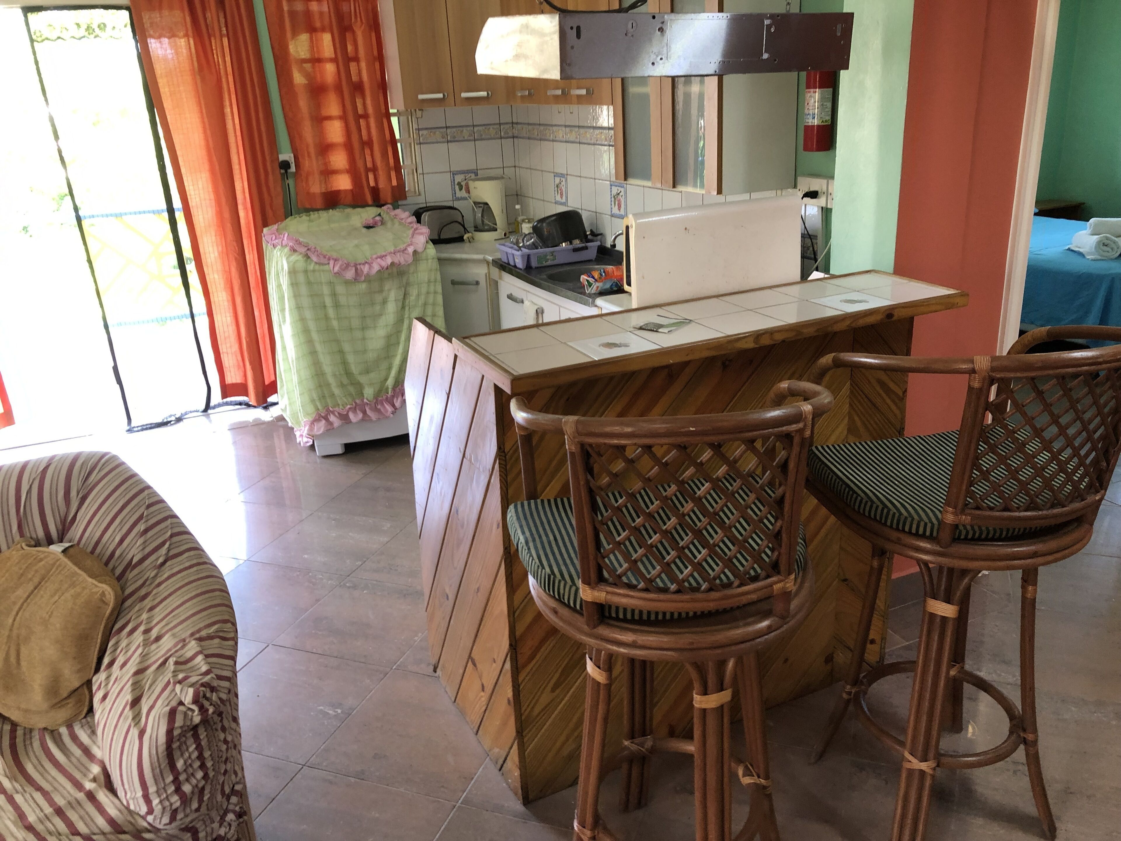 Una cucina accogliente con zona pranzo, con un set di sgabelli da bar e una sedia a righe.