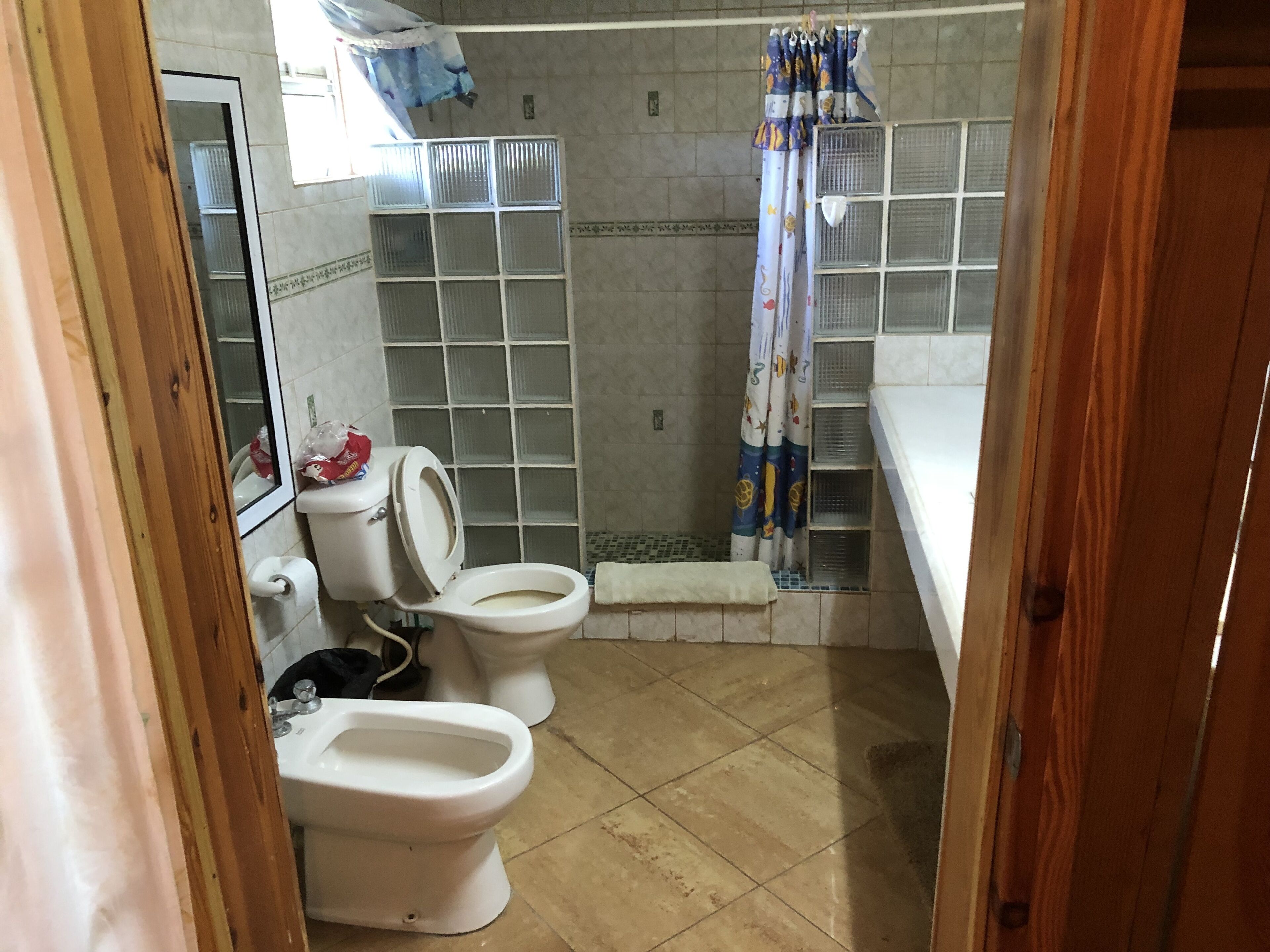 A bathroom with two toilets, a shower, and a sink.