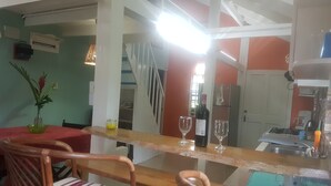 A kitchen with a wooden counter, two chairs, a refrigerator, and a dining table with a red tablecloth. - Coco Mango Suites (Portsmouth)