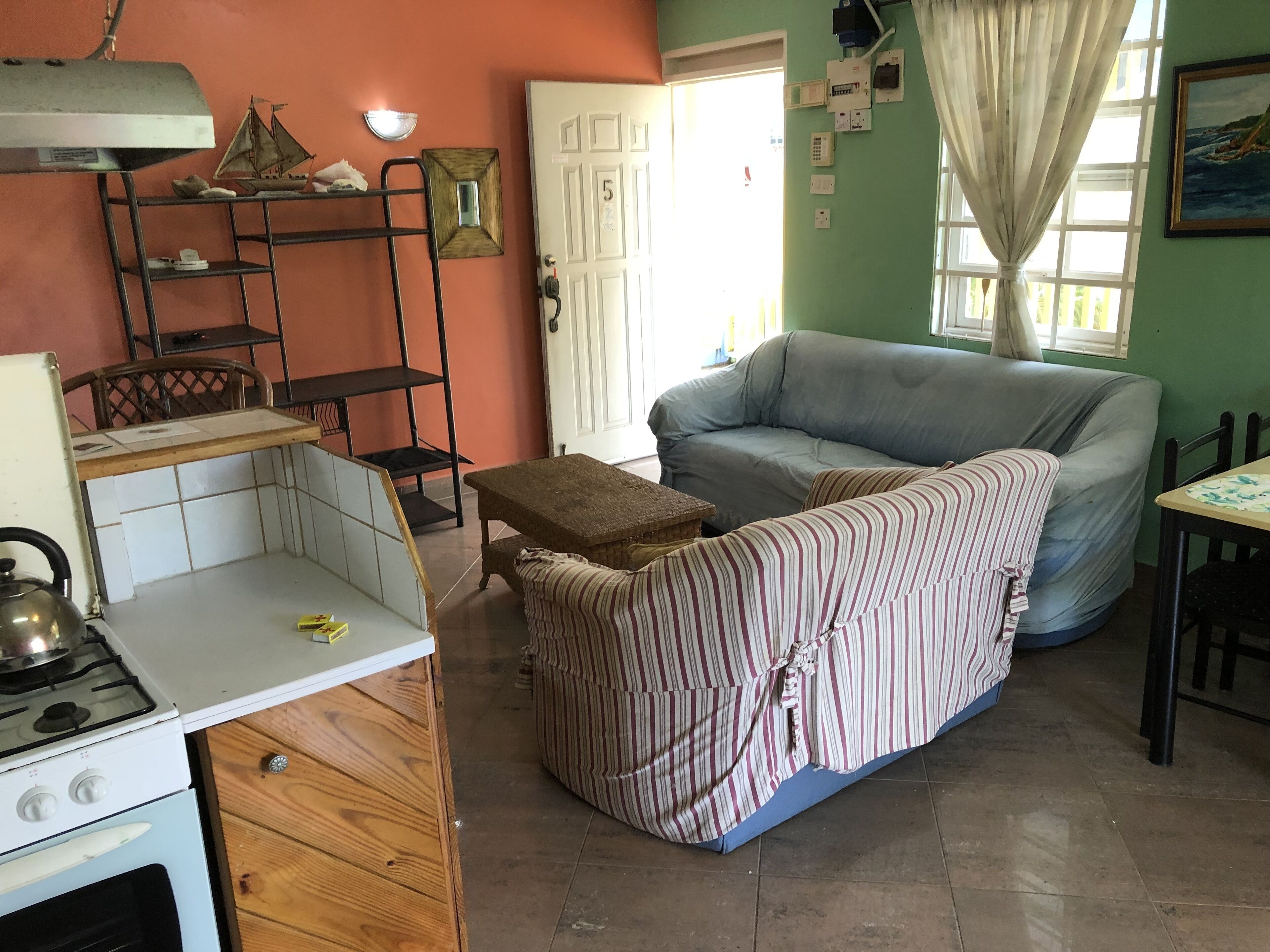 Un espacio habitable compacto con kitchenette, un sofá a rayas y una mesa de comedor.