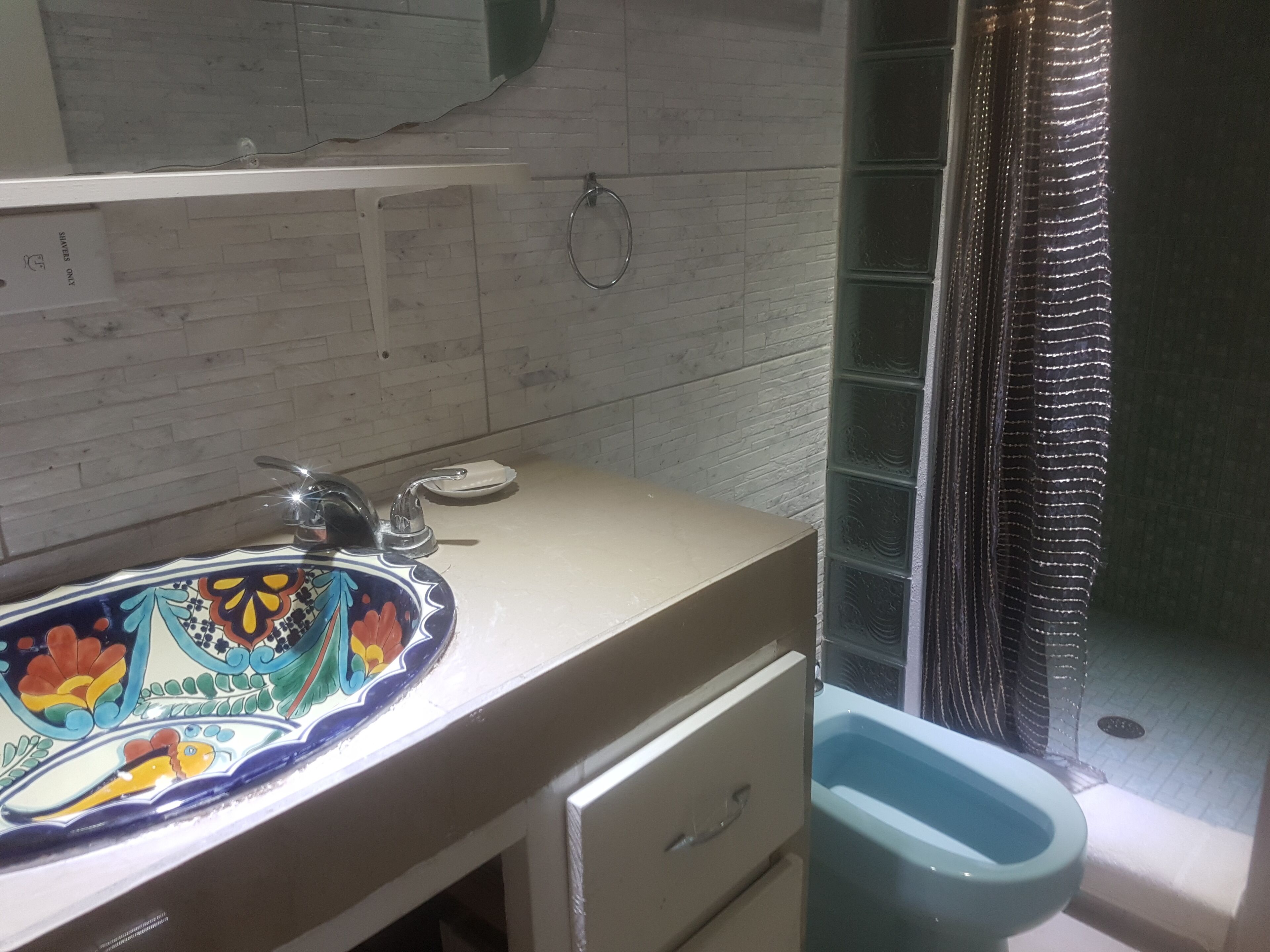 Un bagno con lavandino bianco, uno specchio, un water e una tenda da doccia.
