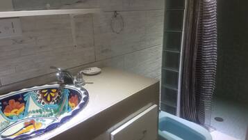 Un bagno con lavandino bianco, uno specchio, un water e una tenda da doccia.
