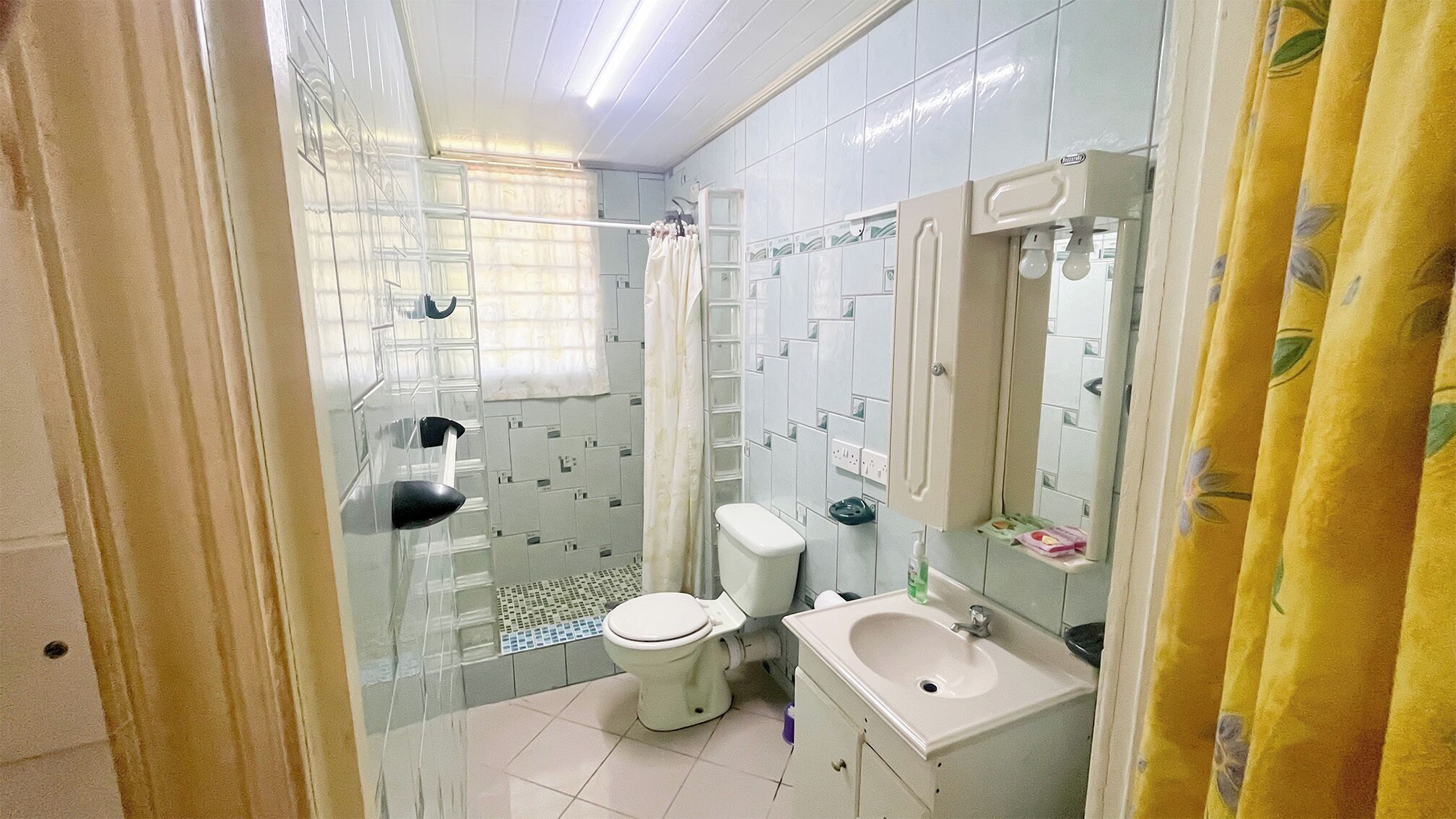 A bathroom with a toilet, sink, and shower area.