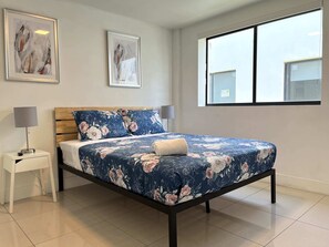 A bedroom with a bed, two bedside tables, a window, and two framed artworks on the wall. - Miami Suite 301 (Miami)
