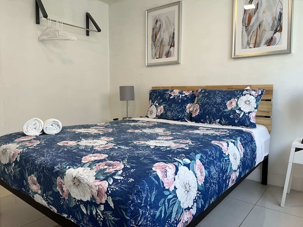 A bedroom with a floral bedspread, a wooden headboard, and two framed artworks on the wall. - Miami Suite 301 (Miami)