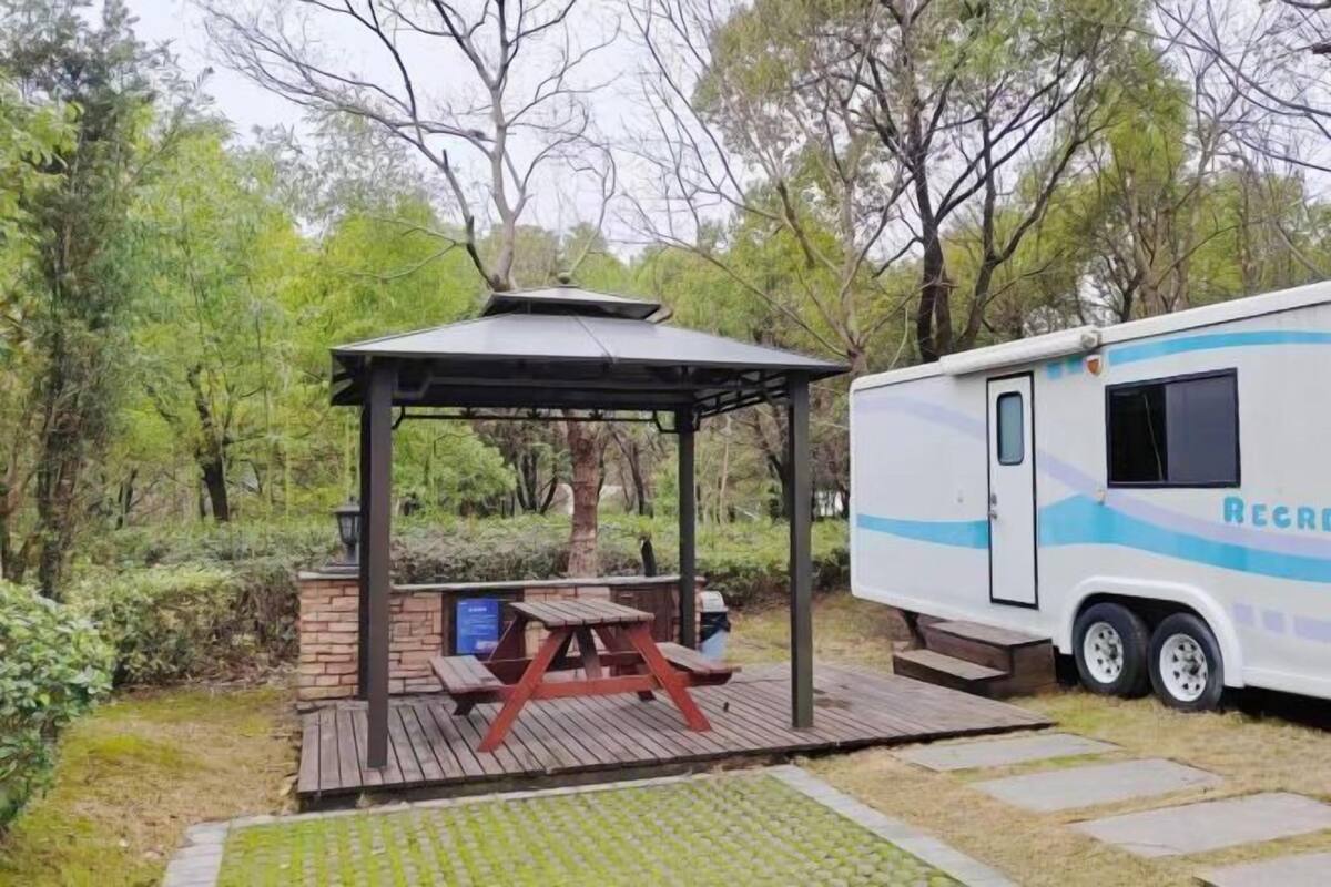 Een recreatiewagen met een overdekte picknickplaats en een gebouw van baksteen.