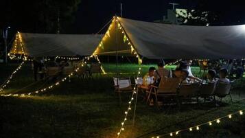 A tented outdoor dining area with string lights and tables set up for guests.