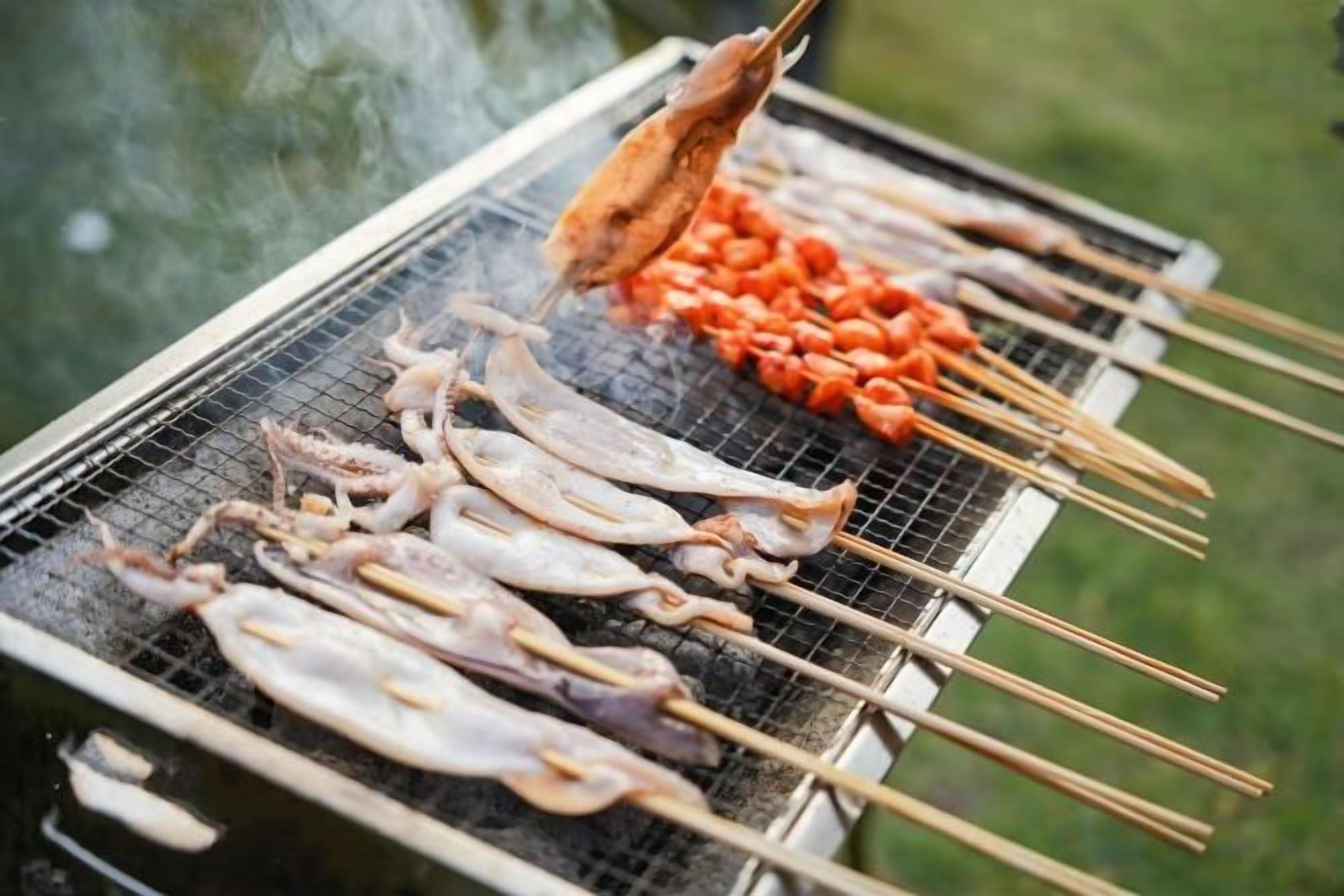Una parrilla con brochetas de carne y verduras.