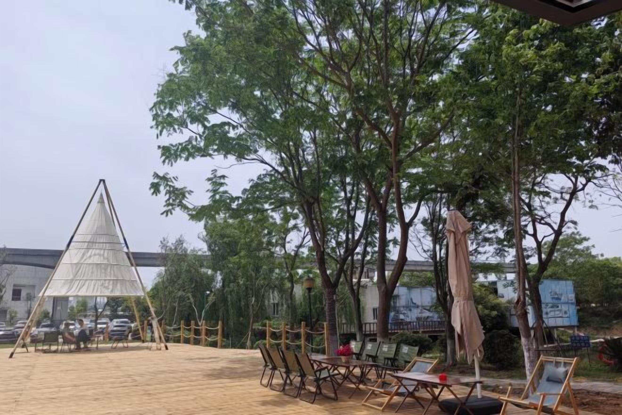 An outdoor seating area with tables and chairs, a pyramid-shaped structure, and trees.