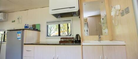 A compact kitchenette with a refrigerator, a microwave, a sink, and a window.