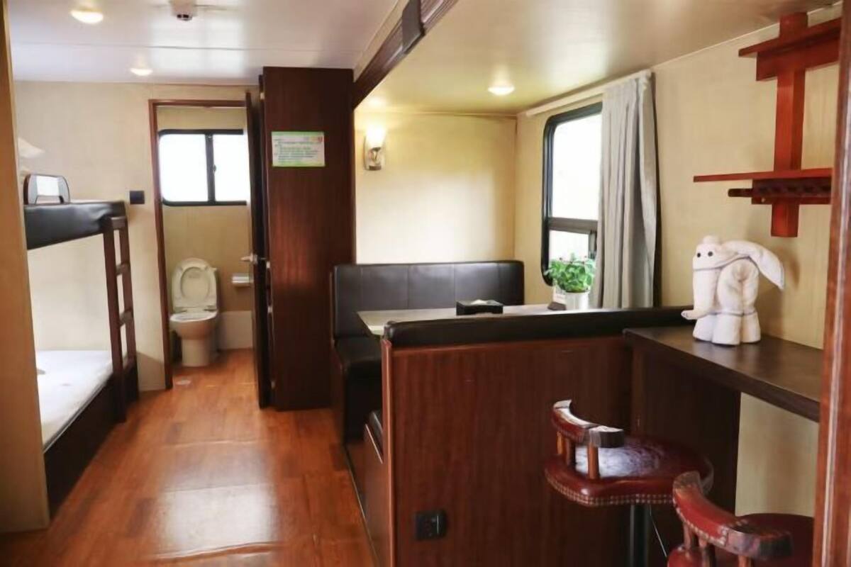 Een compact camperinterieur met een kitchenette, een zitje, een toilet en een raam.
