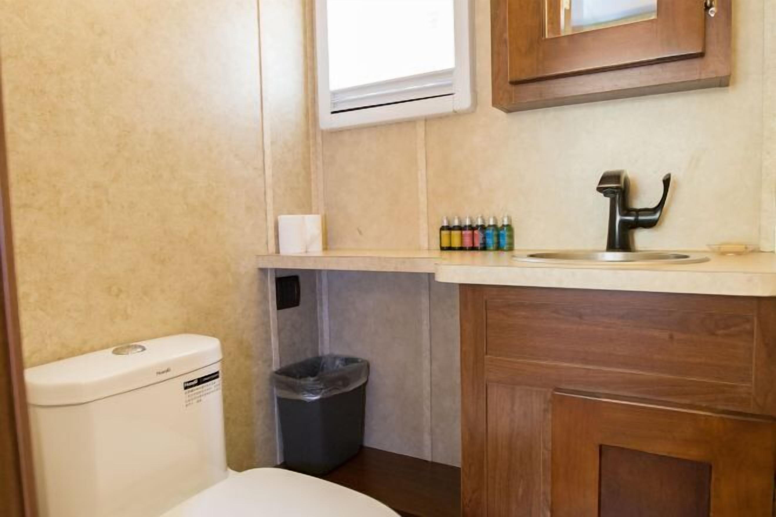 A compact bathroom with a toilet, sink, and trash bin.