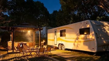 Una caravana con una zona de estar exterior cubierta y una parrilla.