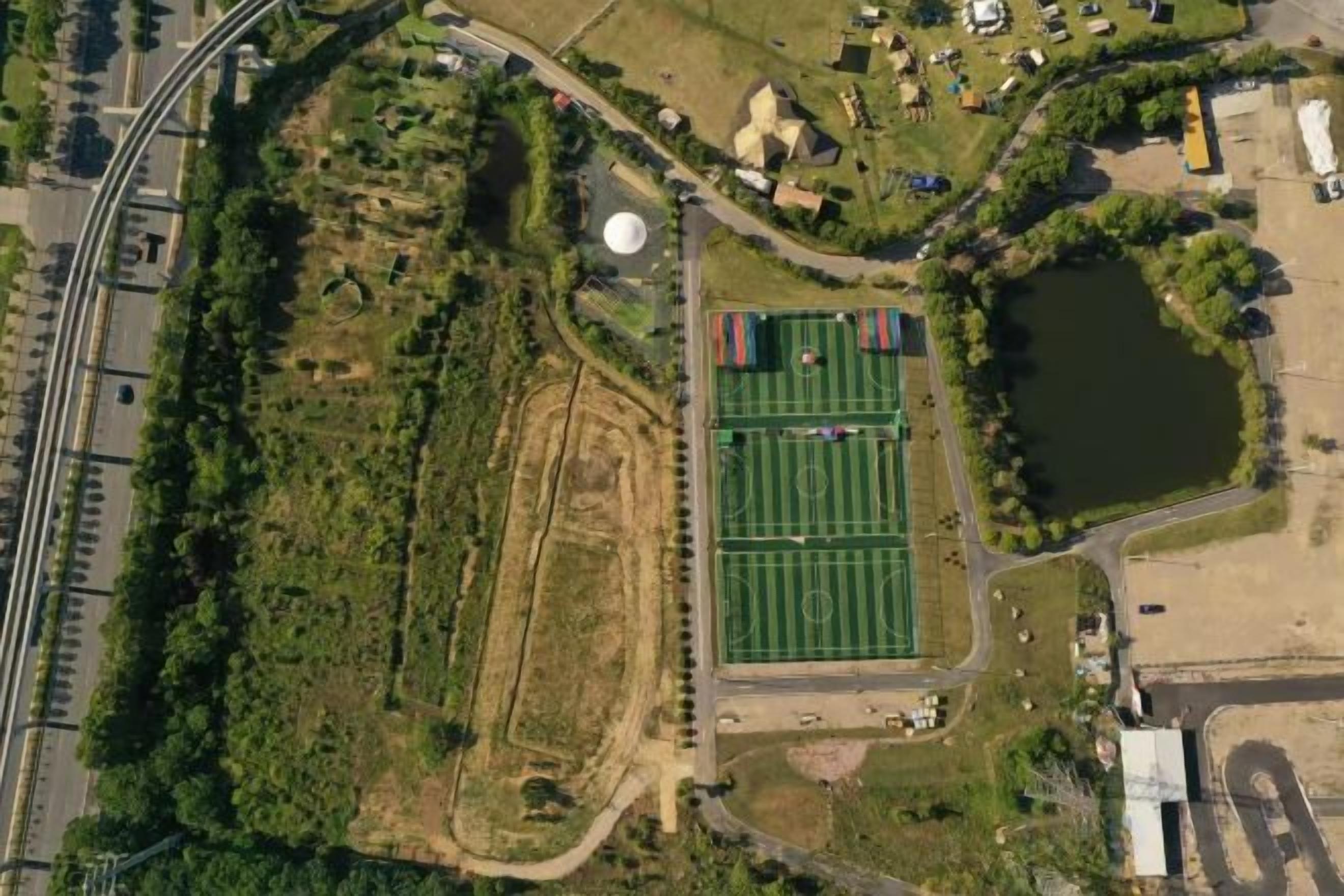 An aerial view of a sports field with a surrounding road and buildings.