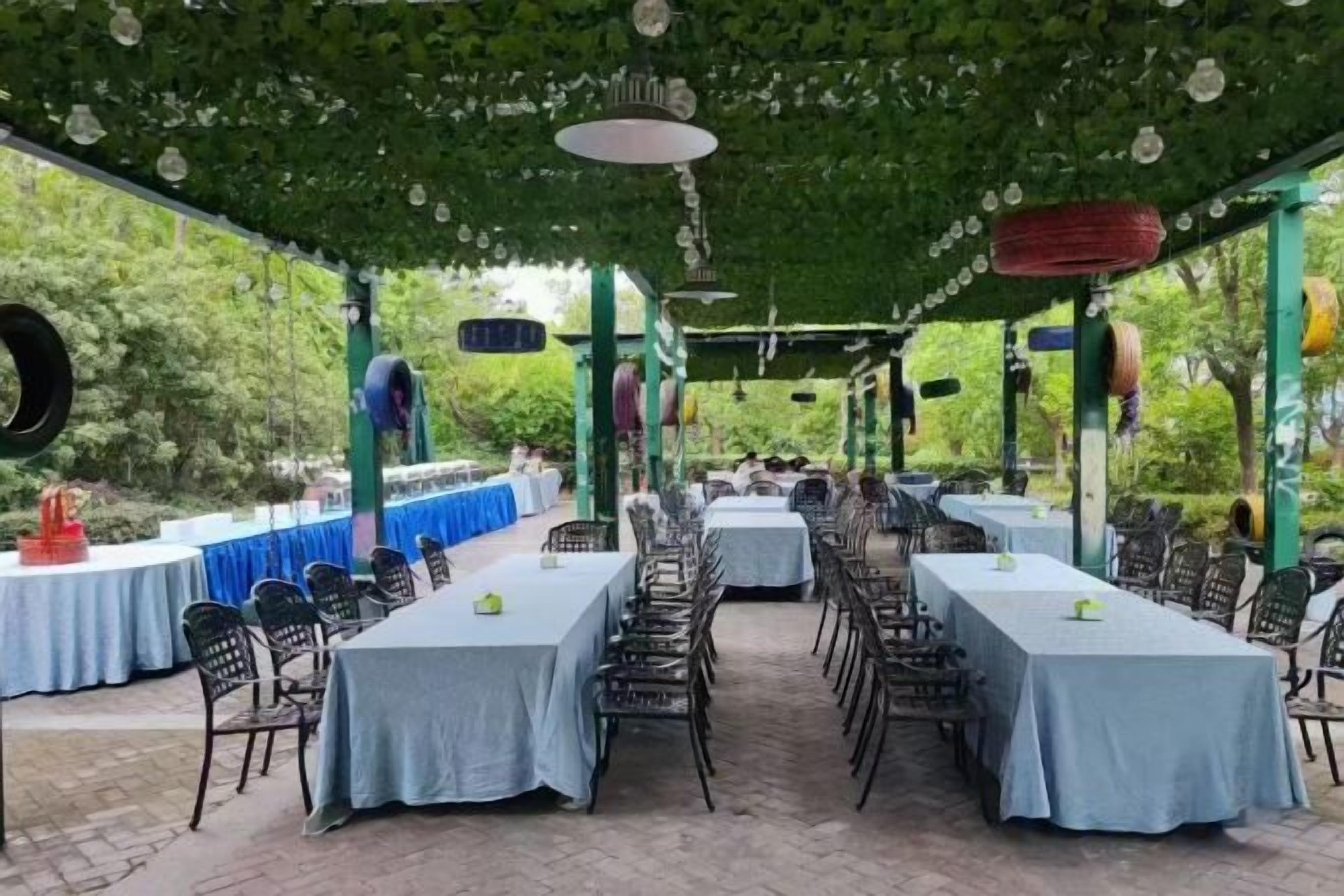 Un espace de restauration en plein air avec des tables recouvertes de nappes, des chaises et un auvent au-dessus.