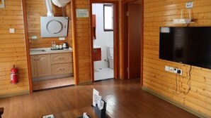 L’intérieur d’une cabane en bois comprend un coin cuisine, un téléviseur et un extincteur.