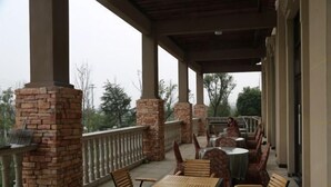 Un espace extérieur abrité, doté de piliers en briques, de tables et de chaises.