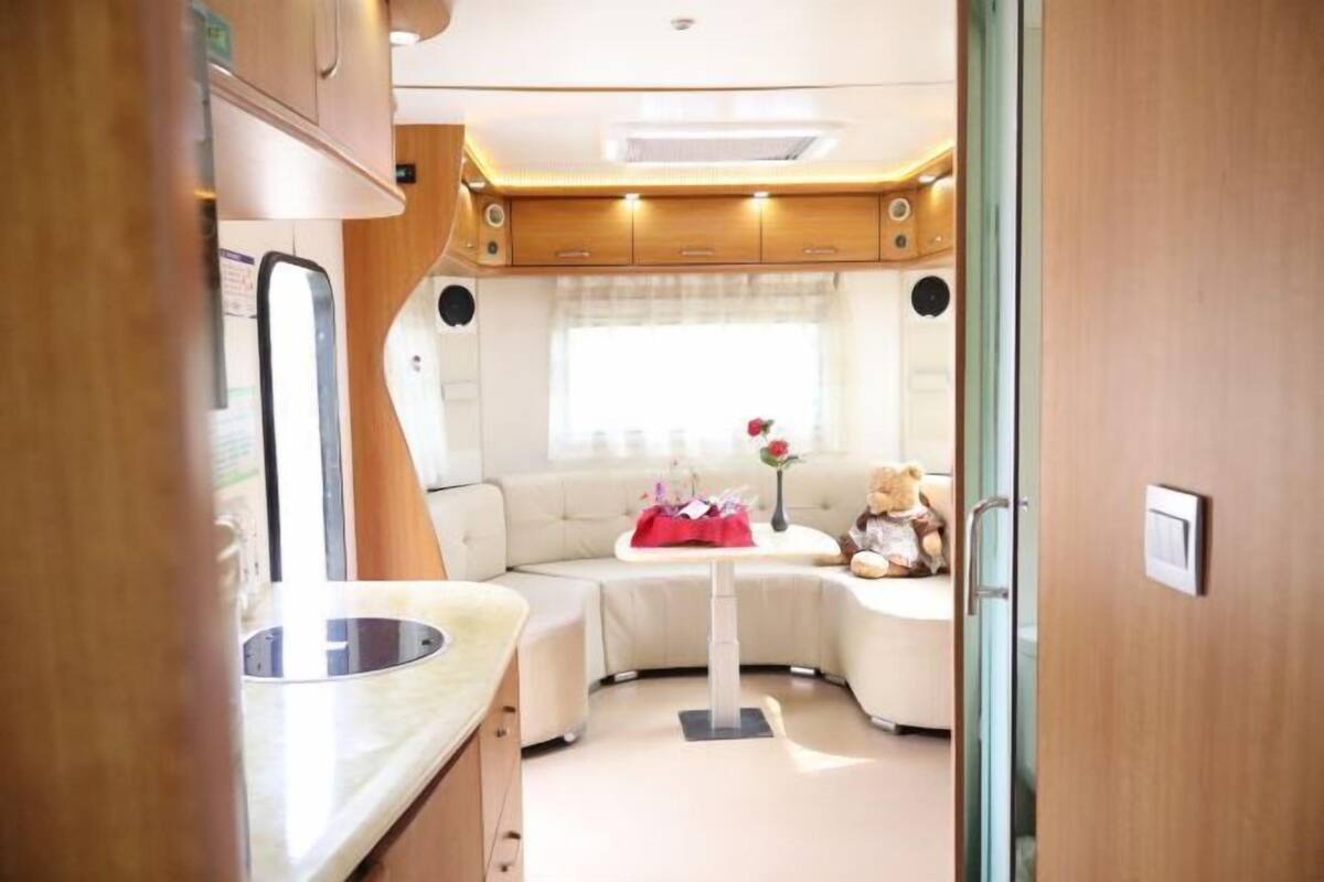 Een compact RV-interieur met een kitchenette, een zithoek en een klein tafeltje met een teddybeer.
