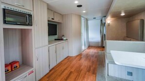 Une cuisine de taille réduite, équipée d’un four à micro-ondes, de placards et d’un plancher en bois.