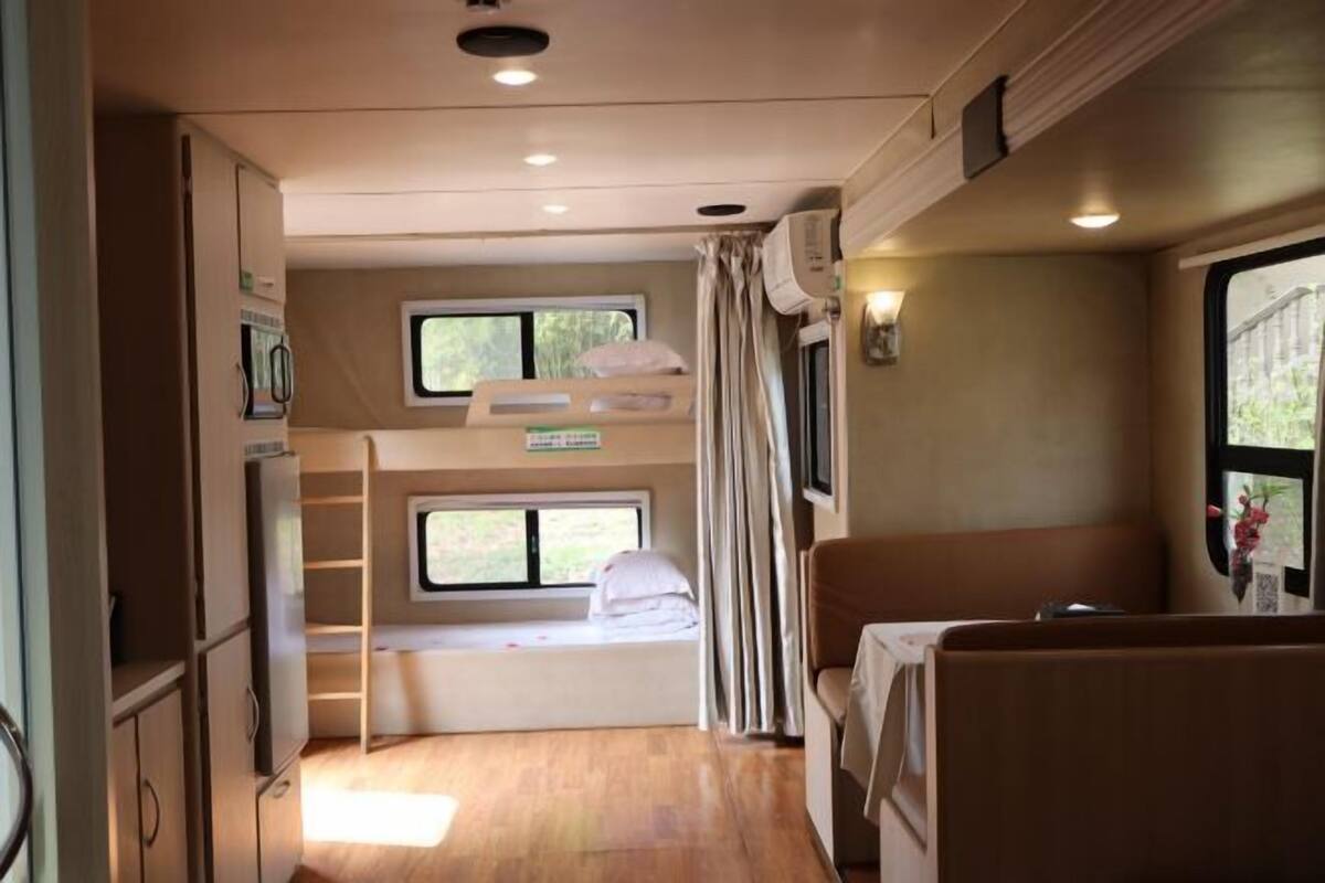 Een compact RV-interieur met stapelbedden, een kitchenette en een zithoek.
