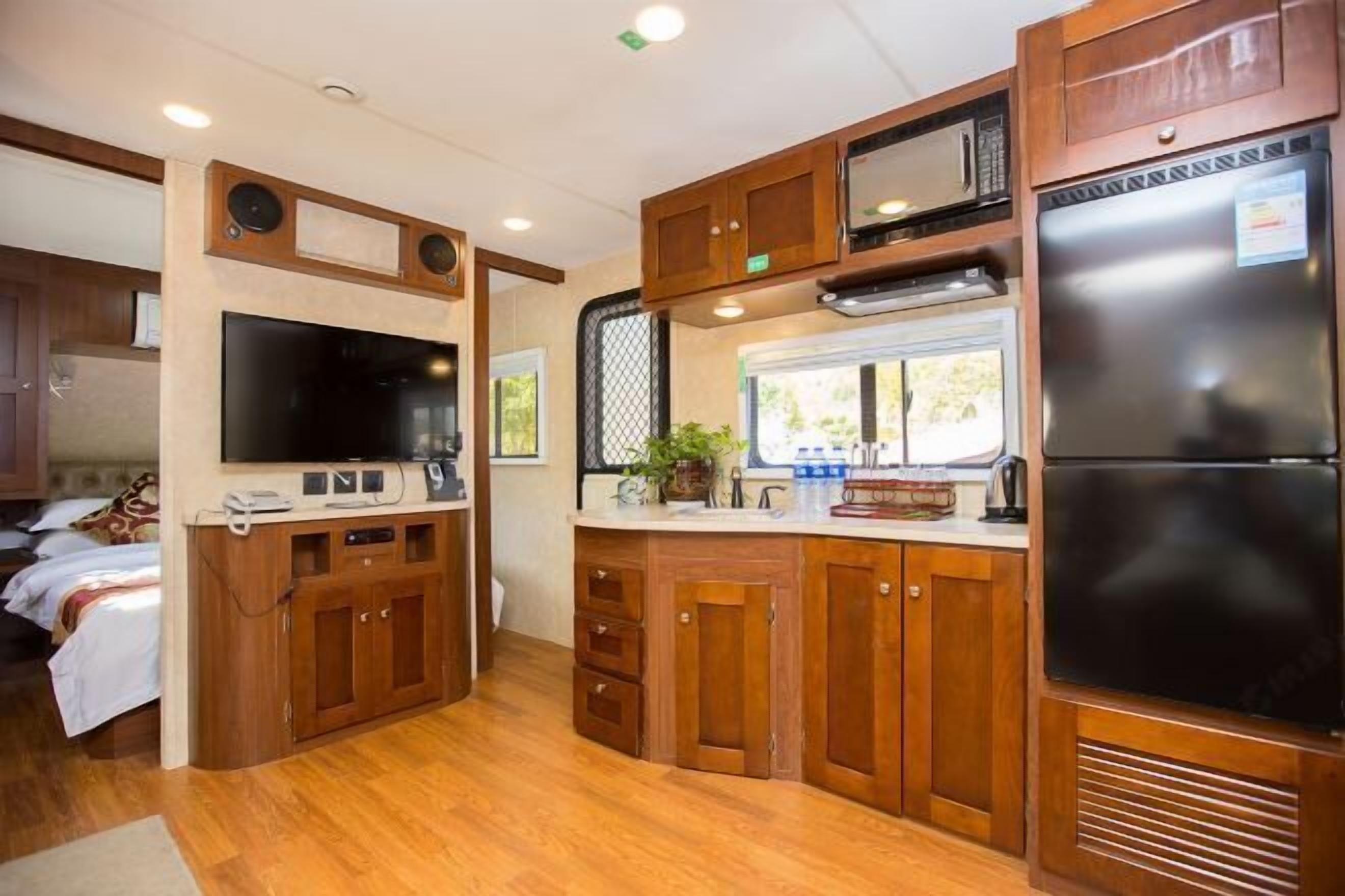 Cocina compacta para autocaravana con armarios de madera, microondas integrado y refrigerador.