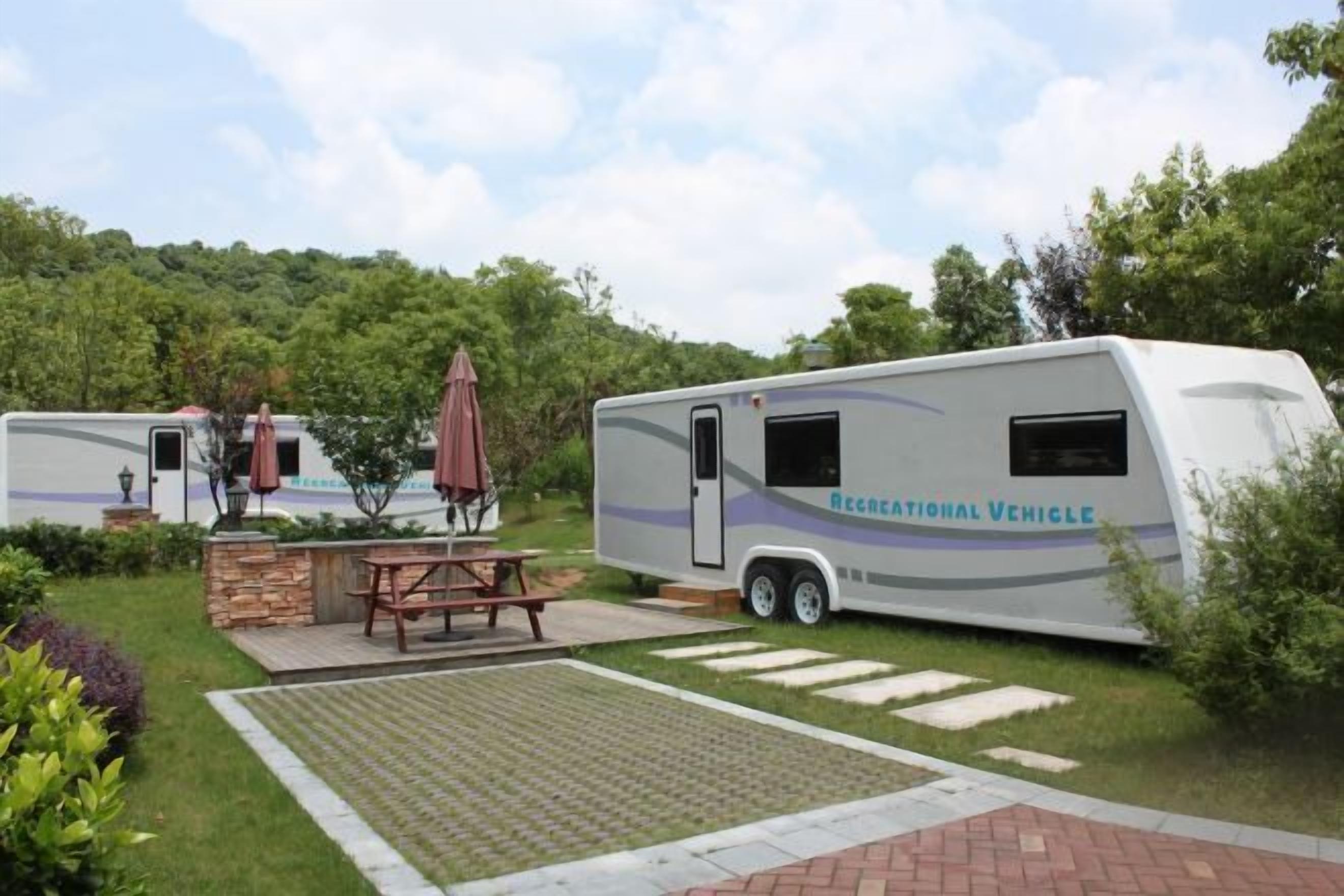 A recreational vehicle with a picnic table and umbrella in a grassy area.