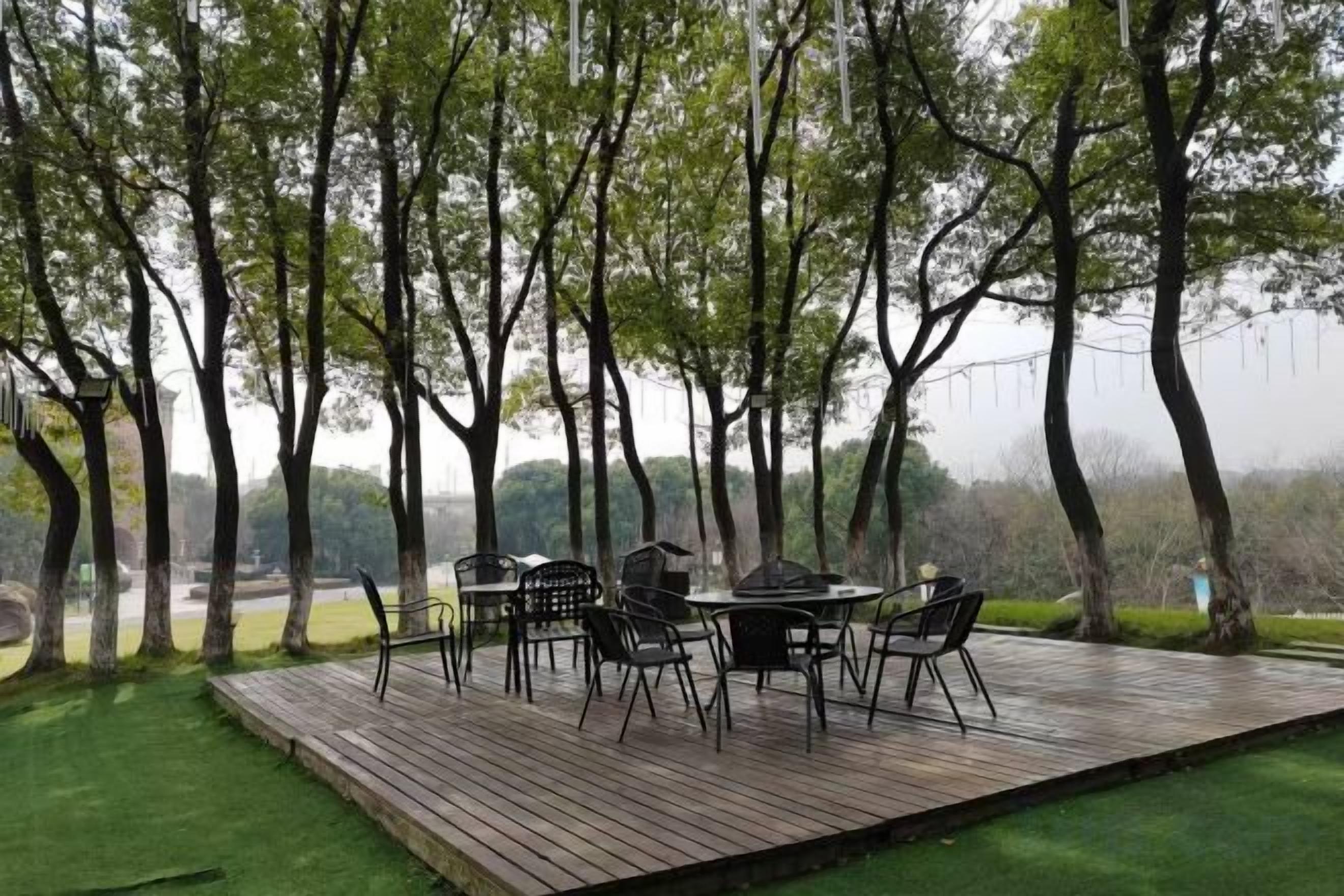 Un área de comedor al aire libre con terraza de madera, rodeada de árboles y vistas al paisaje.