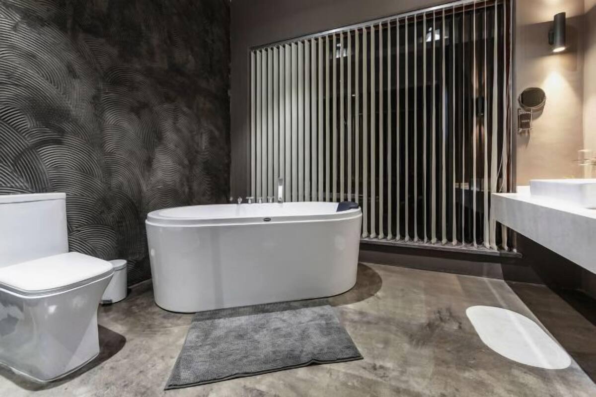 Un baño moderno con una bañera independiente, un inodoro y un tocador con espejo.