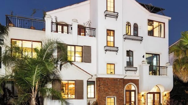 Un edificio de varios pisos con balcones, ventanas amplias y fachada de piedra.