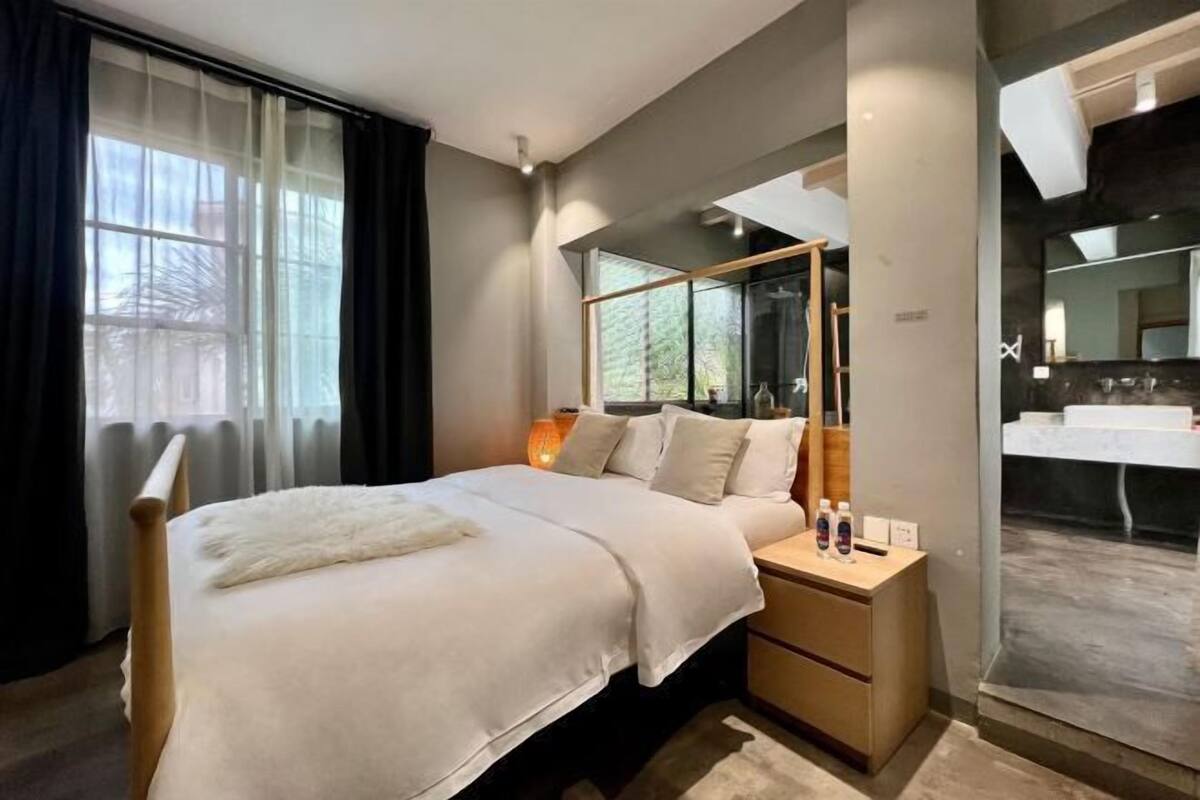 Un dormitorio moderno con cama, mesita de noche y un espejo grande.