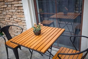 A wooden table with a potted plant, black chairs, and a stone wall.