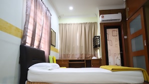 Ein Hotelzimmer mit Bett, Schreibtisch, Stuhl, Kleiderschrank und Klimaanlage.