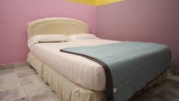 A bed with a white headboard and a blue blanket in a room with pink walls and a yellow ceiling.