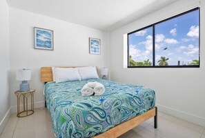 Une chambre à coucher avec un lit, deux lampes fixées au mur et deux tableaux encadrés.