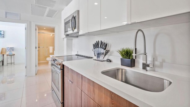 A modern kitchen with white cabinets, stainless steel appliances, and a large sink.