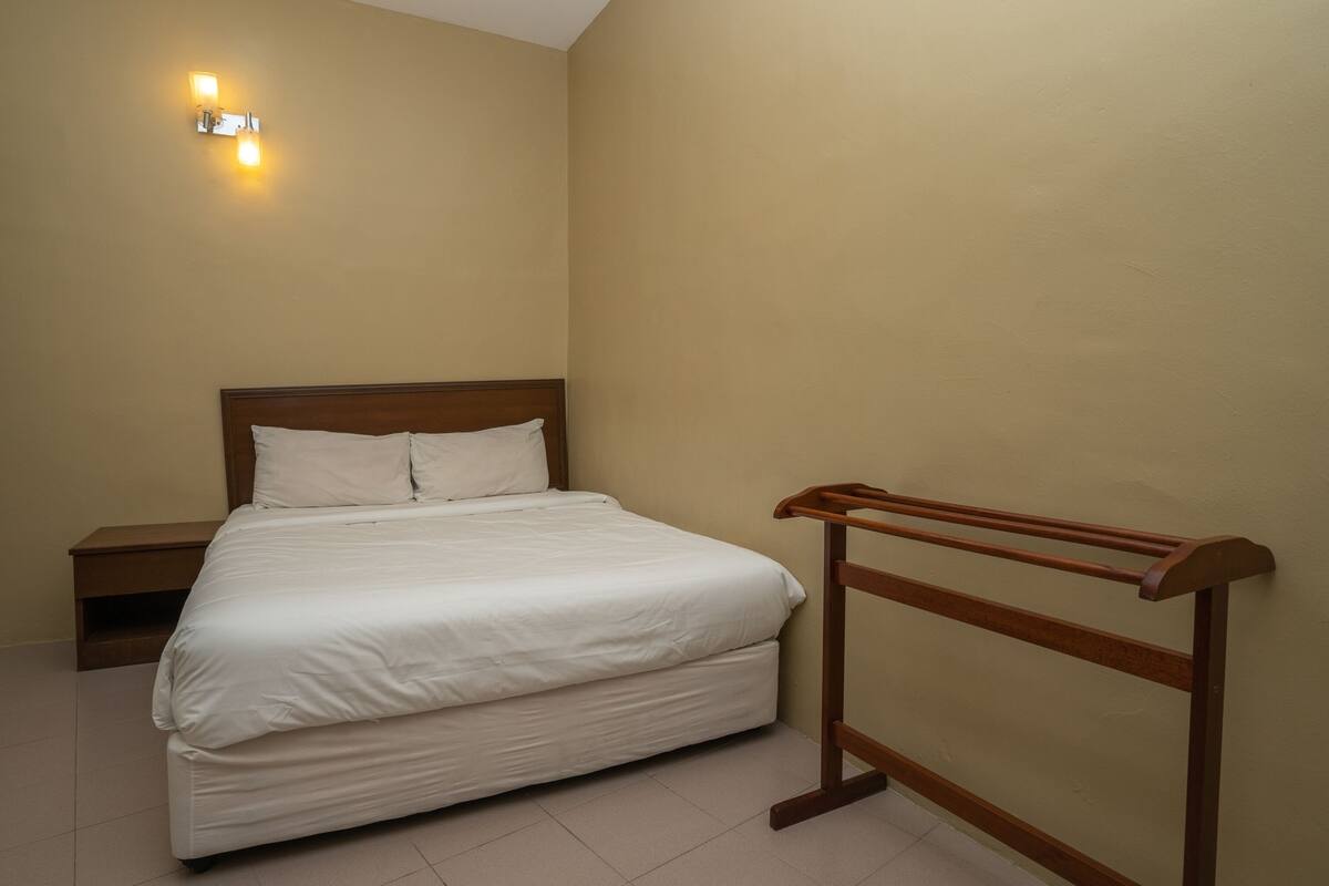 A bedroom with a bed, nightstand, and a wooden bench.