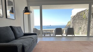 A modern living room with a grey sofa, a black floor lamp, and a view of the sea through large glass doors. - House with sea view for 6 people (São Roque)