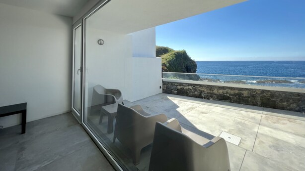 A modern balcony with a glass door, a small table, and two chairs. - House with sea view for 6 people (São Roque)